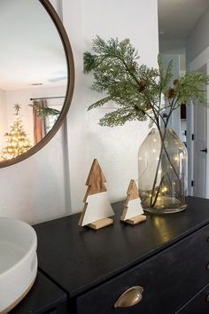 a vase filled with pine cones sitting on top of a dresser next to a mirror