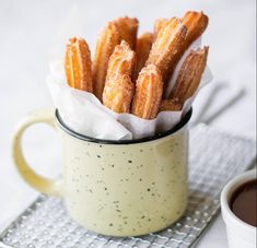 a cup filled with fried food sitting on top of a metal cooling rack next to a white table cloth