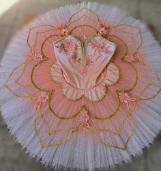 a ballerina's pink and gold tutu skirt with flowers on the bottom