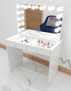 a white vanity with lights on it and a blue chair