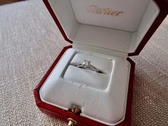 an engagement ring in a red box with the word cartier on it's side