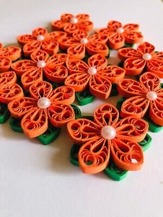 some orange and green flowers on a white surface with pearls in the middle, sitting next to each other