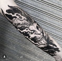 a man's arm with a black and white tattoo design on the left forearm