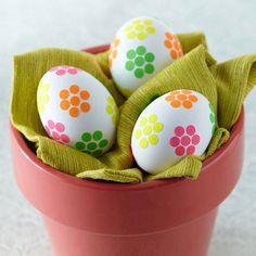 three decorated easter eggs in a red bowl