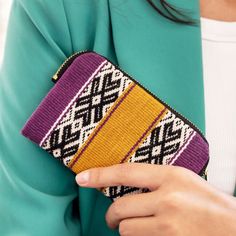 a woman is holding a colorful purse in her hand