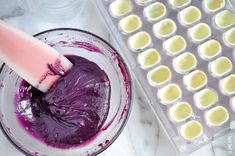 a purple substance in a glass bowl next to an egg carton