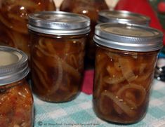 several jars filled with pickles sitting on top of a blue and white checkered table cloth