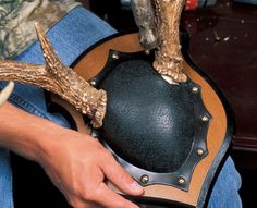 a person holding a black and brown guitar case with deer antlers on the top