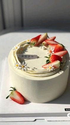 a white cake with strawberries and daisies on it