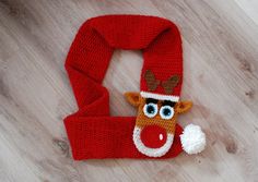 a red knitted scarf with a reindeer head on it and a white pom - pom