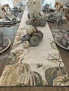 the table is set for thanksgiving dinner with pumpkins and gourds on it