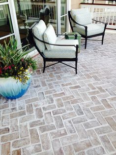 two chairs sitting on top of a patio next to a potted plant