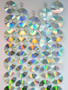 several cds are hanging on a wall with chains attached to the discs, and one is being