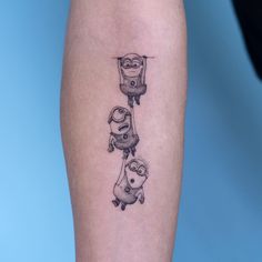 a tattoo on the leg of a person with two small cartoon characters hanging from it