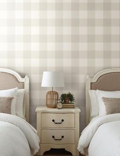 two beds with white linens and pillows in a bedroom next to a wallpapered wall