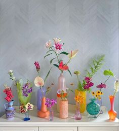 there are many vases with flowers in them on the table next to each other