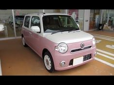 a pink and white car parked in front of a building