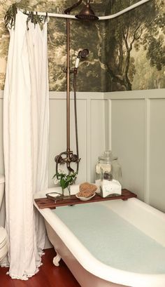 a bath tub sitting next to a white toilet in a bathroom under a painting on the wall