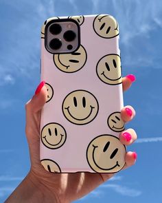 a woman's hand holding up a phone case with smiley faces on it