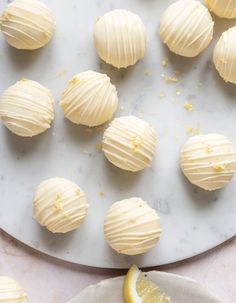 lemon meringue truffles on a white plate with a slice of lemon