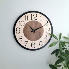 a wooden clock on the wall with numbers and numerals in black and white