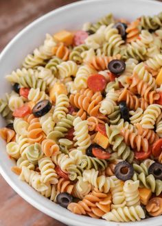 a white bowl filled with pasta and olives