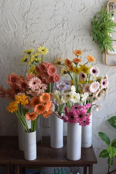 several white vases filled with different colored flowers