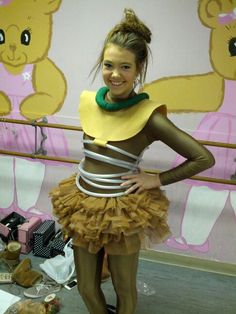 a woman in a costume standing next to a wall with teddy bears painted on it