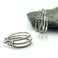 two silver rings sitting next to each other on top of a rock with stones in the background