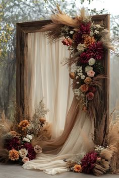 a photo frame decorated with dried flowers and feathers for an outdoor wedding ceremony or special event