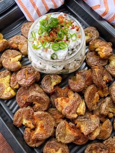 a tray filled with potatoes covered in sauce and toppings next to other food items