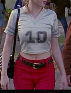 a woman wearing red pants and a white shirt with the number ten on it's chest