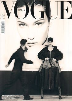 a man and woman standing in front of a magazine cover with an advertisement for the italian fashion brand