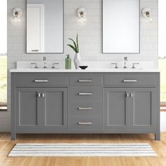 a bathroom with two sinks and mirrors on the wall next to a rug in front of it