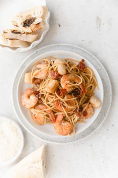 pasta with shrimp and tomato sauce in a bowl next to garlic bread on a plate