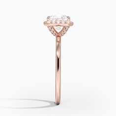 a rose gold engagement ring with an oval cut diamond in the center and side stones