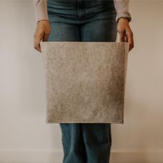 a person holding up a piece of paper in their hands, with the bottom part of her pants visible