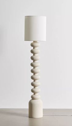 a white table lamp sitting on top of a wooden table next to a light bulb