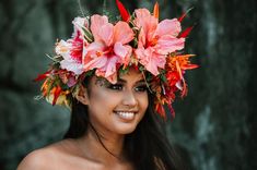 a woman with flowers in her hair smiling at the camera while wearing a flower crown