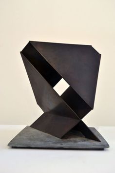 an abstract metal sculpture sitting on top of a cement slab