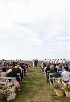 an outdoor ceremony with people sitting in chairs