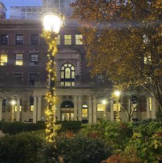 a street light in front of a large building with lights on it's sides