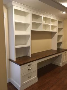 an empty room with white shelves and drawers on the wall next to a wooden floor