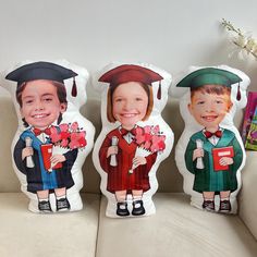 three children's graduation pillows sitting on a couch