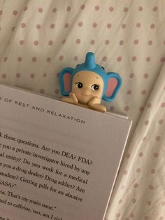 a book with a toy elephant on top of it sitting next to a bed sheet