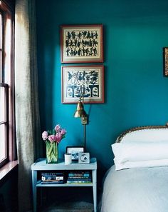 a bedroom with green walls and pictures on the wall above it, along with a white bed