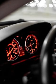 the dashboard of a car is lit up with red and white gauges on it