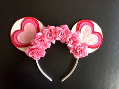 two heart shaped headbands with pink flowers and hearts on the top, sitting on a black surface