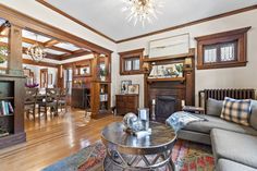 a living room filled with furniture and a fire place under a chandelier on top of a hard wood floor