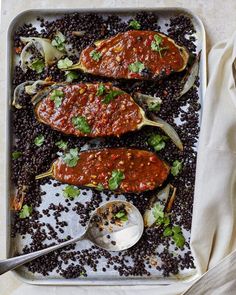 an overhead view of food on a tray with spoons and utensils next to it